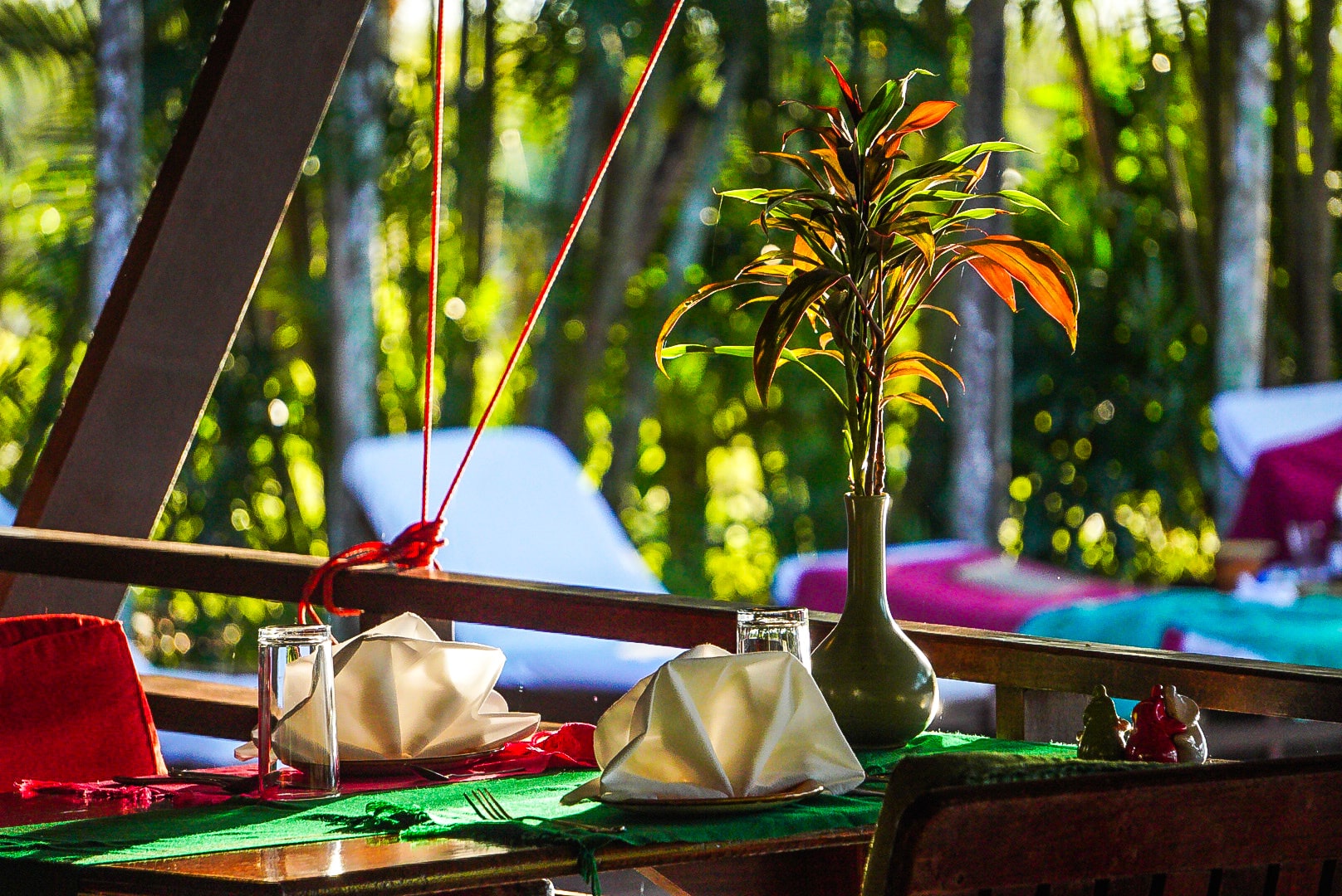 A restaurant table set with folded napkins and tropical flowers