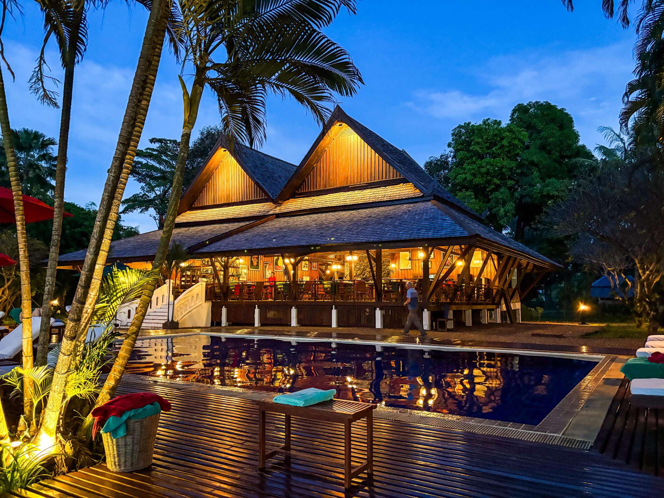 The illuminated timber restaurant reflected in the swimming pool at dusk